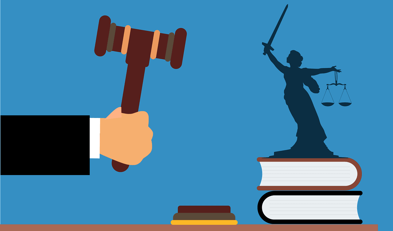 Une main menaçante tient un marteau de juge, face à une mini-statut hissée sur 2 livre etbrandissant une épée de la main droite, la balance de la justice en main gauche