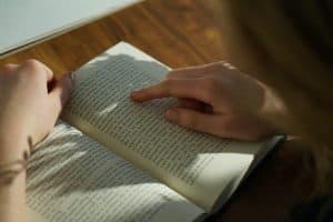 Personne qui lit un livre en suivant les lignes avec son doigt.