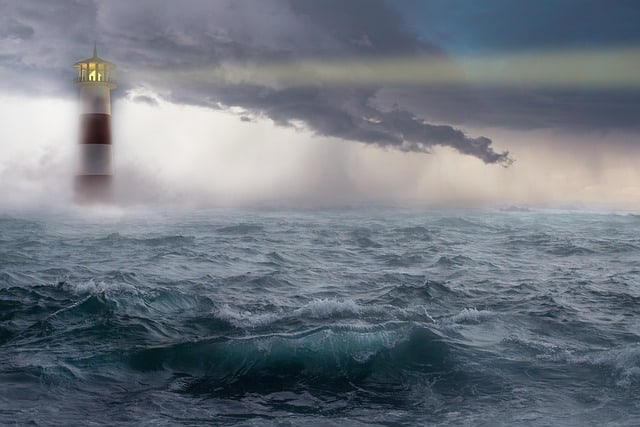 Image d'un phare illuminé au milieu d'une mer agitée, sur fond de ciel menaçant. Crédits en légende.